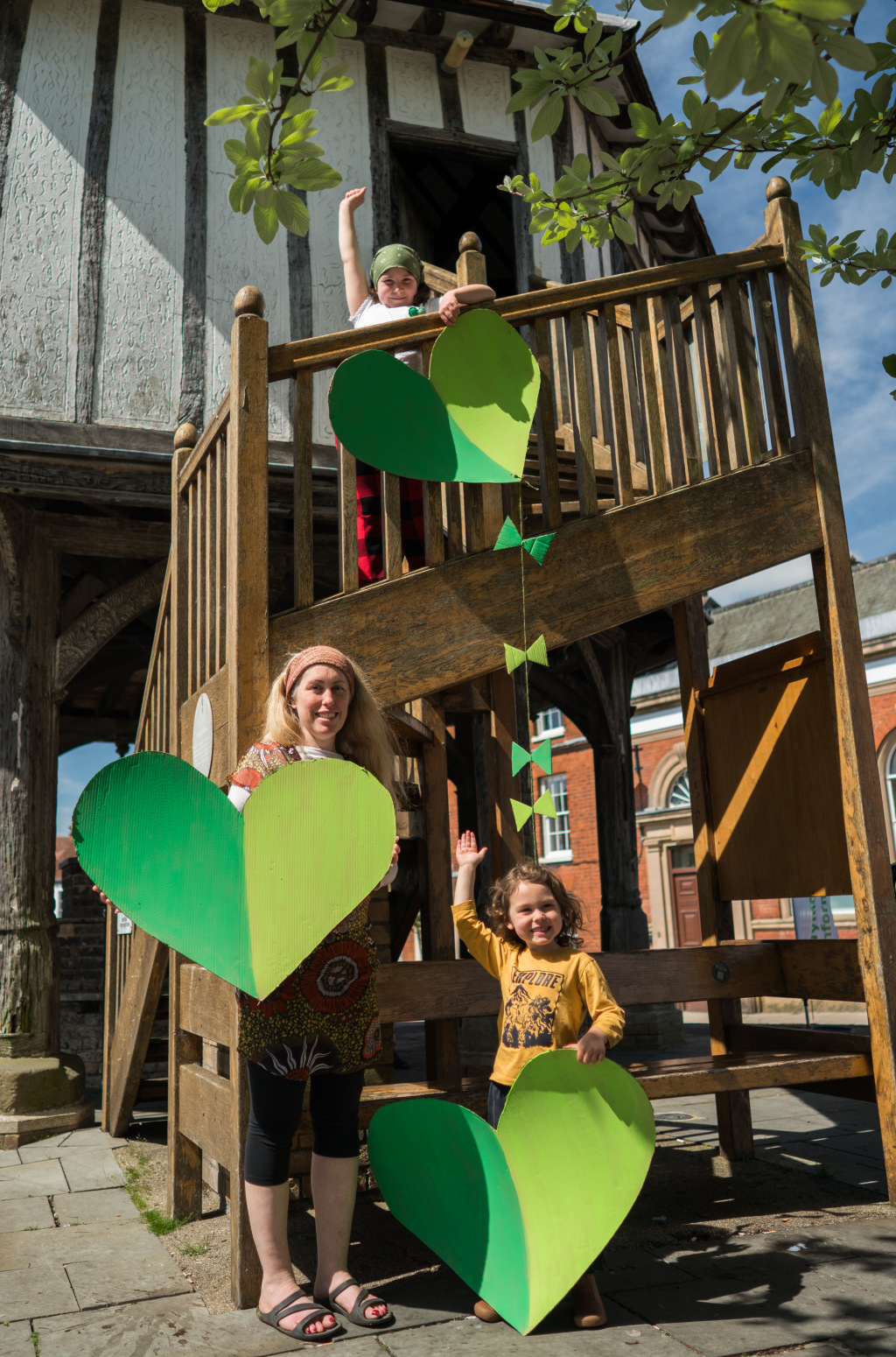 Lady and two girls hold green hearts on staircase