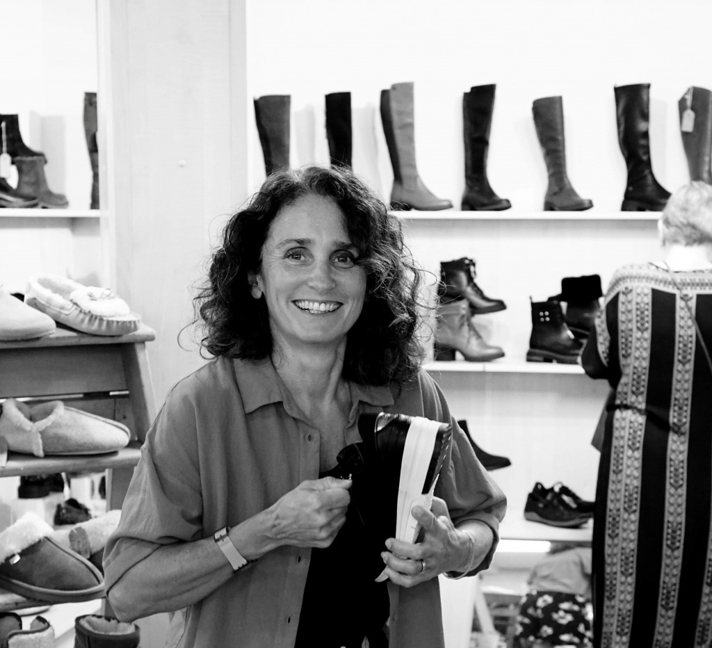 Lady with dark curly hair holding shoes in shop
