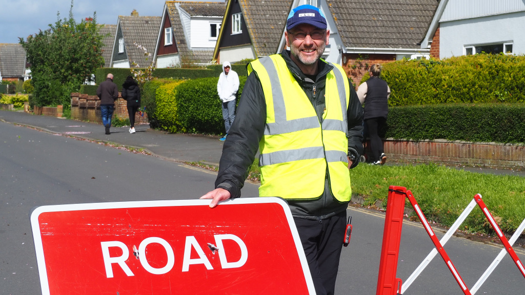 Man in high visibility vest guards road closure barrier